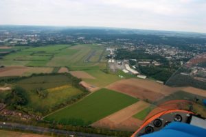 Blick aus dem Tragschrauber über Felder und eine Ortschaft