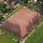 Luftaufnahme eines Sportplatzes zwischen Wohnhäusern