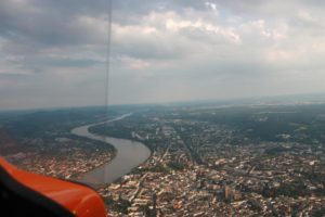 Luftaufnahme des Rheins mit angrenzender Stadtbebauung aus dem Tragschrauber